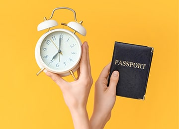 Manos con pasaporte y reloj despertador